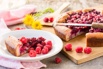 A piece of cake with raspberries and fresh berries on the plate