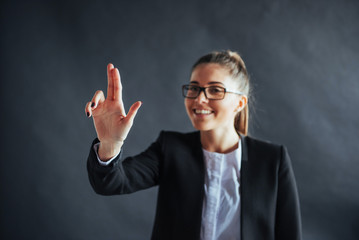 Happy business woman shows finger up, standing on a black background in the studio, friendly, smiling, focus on hand.