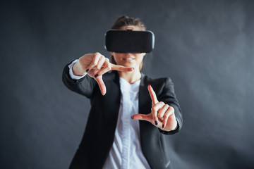 Happy woman on background in the studio gets the experience of using VR-glasses virtual reality headset