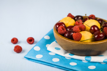 Ripe berries in a plate on a wooden table.