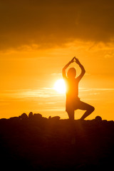 Yoga Woman doing yoga pose outside in sunset
