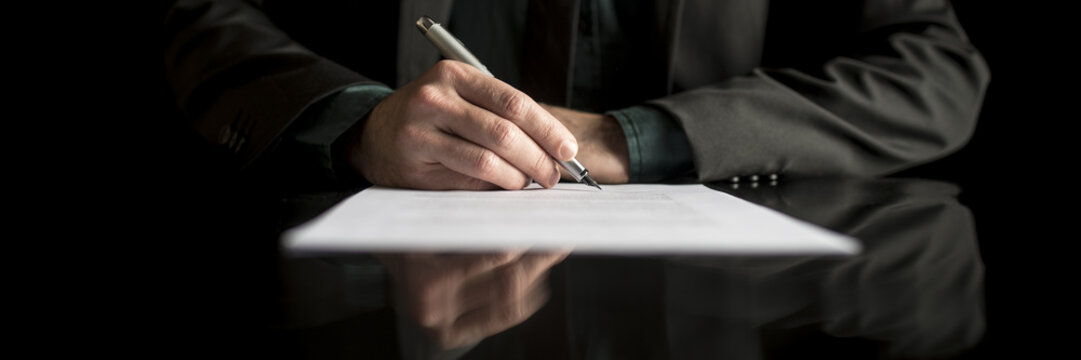 Wide cropped view of a businessman in business suit signing contract