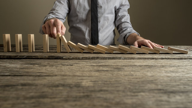 Front view of a businessman stopping domino effect with his finger