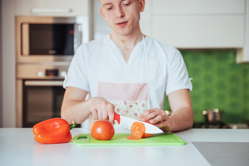 man cuts vegetables together in the kitchen