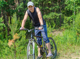 Fototapeta premium Young man riding a bicycle in the woods