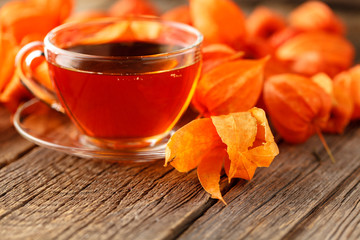 Cup of tea with autumn leaves background on wooden table / fall tea background