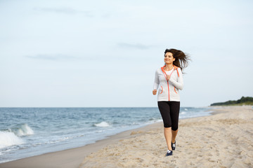 Young woman running, jumping on beach 