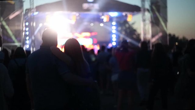 Couple in love at a music concert. Blurred and lighted Crowd dancing