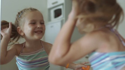 Smiling cute girl having fun and looking at reflection in mirror and kisses.