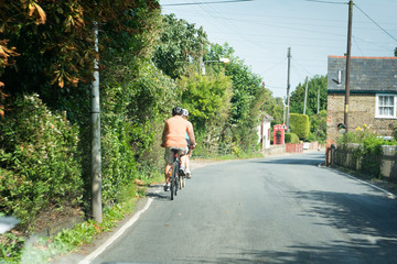 Fototapeta na wymiar Cyclists ride bike through a quiet country lane