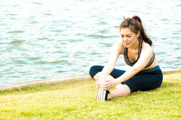 Fototapeta na wymiar Asian sport woman exercise and stretching by yoga in park on grassland and lake background