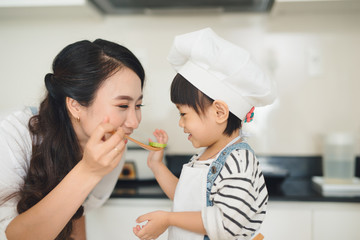 Happy family in the kitchen. Mother and child daughter are preparing the vegetables and fruit.