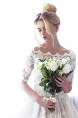 Young beautiful bride. Wedding hairstyle, blond hair, wedding dress, makeup and bride's bouquet.