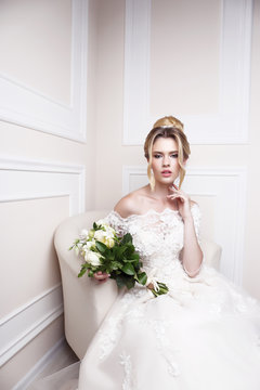 Young beautiful bride. Wedding hairstyle, blond hair, wedding dress, makeup and bride's bouquet.