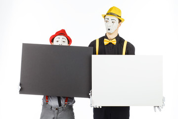 Two funny mimes holding a white blank on a white background.