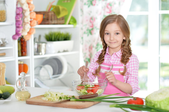 little girl preparing vegetable salad