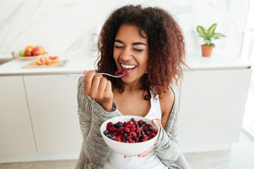 Young woman eating healthy food in kitchen