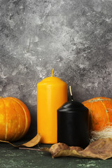 Ripe pumpkins, orange and black candle on a green background