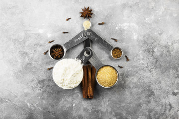 The fir-tree made of ingredients for Christmas cookies (flour, cane sugar, anise, carnation, cinnamon, nutmeg) on a gray background. Top view. Food background
