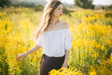 Naklejka na ściany i meble Beautiful girl in a field with flowers