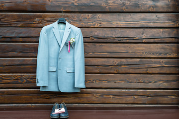 Stylish elegant wedding groom suit with buttonhole hanging on wooden background with copy space....