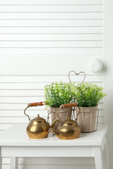 Brass teapots on white door background