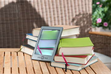 Bücherstapel oder E-Bookreader für die Freizeit im Sommer