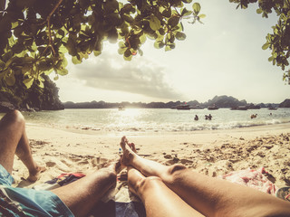 legs of romantic couple relaxing on a sandy tropical beach, Monkey island, Lan Ha bay, Vietnam -...