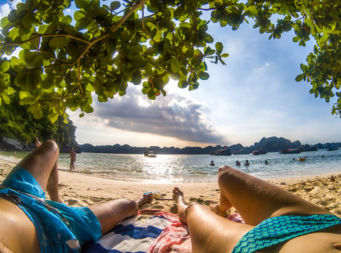 legs of romantic couple relaxing on a sandy tropical beach, Monkey island, Lan Ha bay, Vietnam - holiday concept
