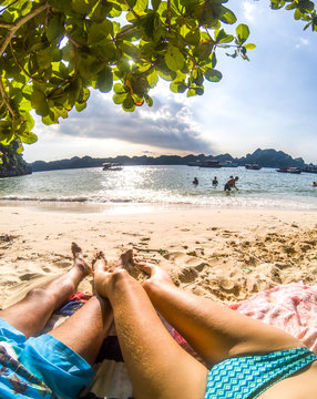 legs of romantic couple relaxing on a sandy tropical beach, Monkey island, Lan Ha bay, Vietnam - holiday concept