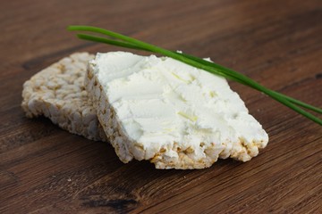 Two rice cakes, one with cream cheese and chives, other one bare