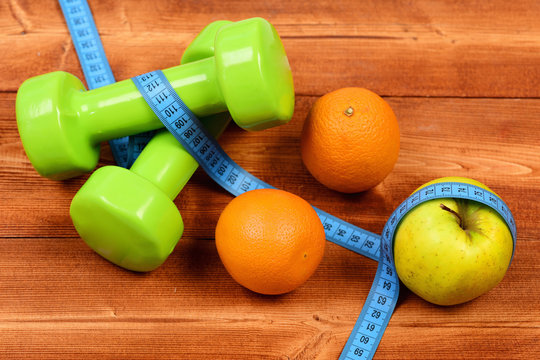 dumbbells weight with measuring tape, apple, orange, diet concept