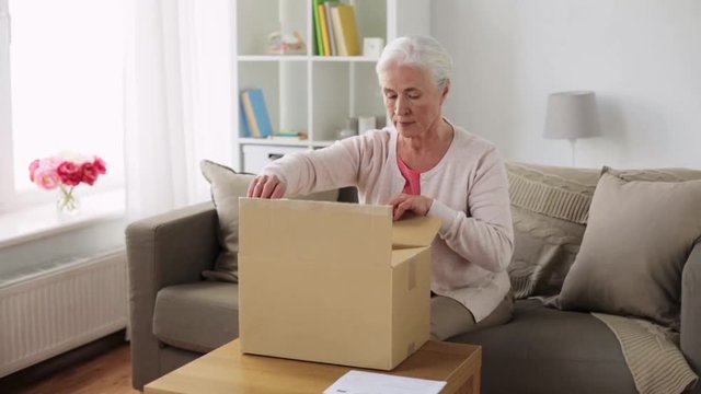 senior woman opening parcel box at home