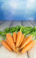 Ein Bündel Möhren auf einem Holztisch vor blauem Hintergrund, Textfreiraum,
