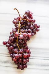 Bunches of fresh ripe red grapes on a marble table. Close up. Selective focus