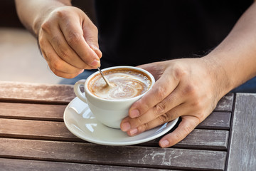 Man hand holding cup of coffee on old wooden table