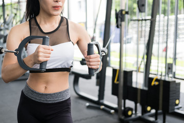 Fototapeta na wymiar young woman execute exercise with machine in fitness center. female athlete pump up muscle with cable crossover in gym. sporty girl working out in health club.