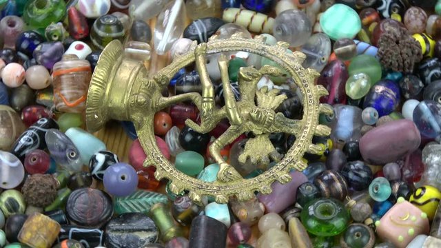 Dancing god lord Shiva brass sculpture souvenir rotating on ancient indian beads background
