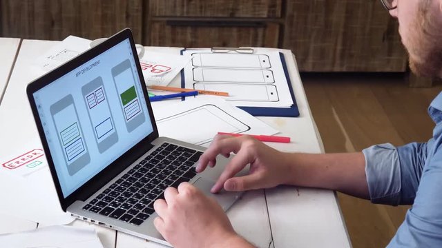 UX designer creating mobile app prototype on his laptop computer
