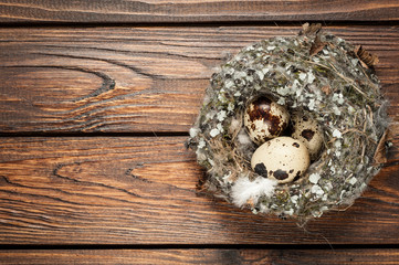 quail eggs in a nest over old wooden background top view