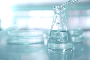 pipette drop water in flask with blur petri dish in medical science laboratory background