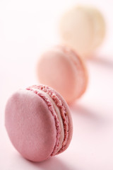 Colorful macarons on a pink background. French sweets lined up on a pink paper