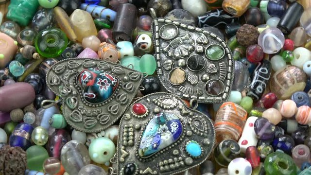 Rotating colorful various indian  ancient pendants on old  beads background

