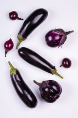 Purple eggplants of different color and variety on the white background.. Top view.