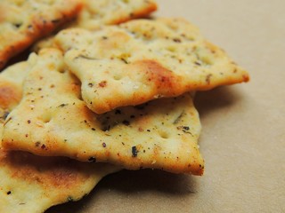 Flatbread crisps with italian herb on brown background. Oven baked snack crackers. Perfect for snacking, topping or dipping.