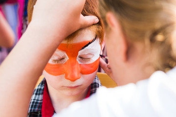 Child boy face painting, making tiger eyes process