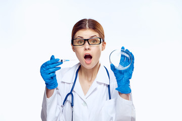 a female doctor holds a petri dish and a syringe