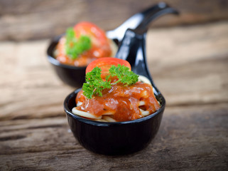 Spaghetti with tomato sauce on wooden table.