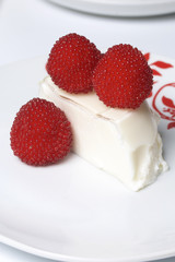Sour cream jelly, decorated with raspberries. Lies on a plate. On a white background.