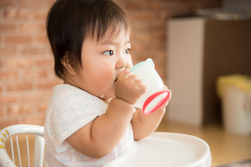 椅子に座って飲み物を飲む赤ちゃん